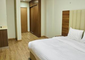 1 dormitorio con 1 cama blanca grande y suelo de madera en غرف فندقية هارودز, en Yeda