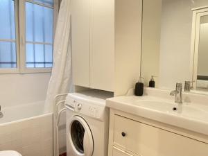 a white bathroom with a washing machine and a sink at Abesse 3 rooms Flat in Paris