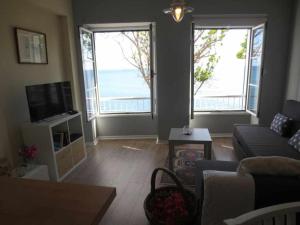 a living room with a couch and two large windows at Barreirinha II Perto da Cidade Velha Com Vista do Oceano de Nice in Funchal