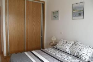 a bedroom with a bed and a wooden closet at GuestReady - Tamariz Cosy Stay in Caniço