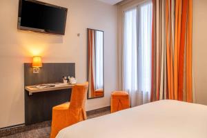 a hotel room with a bed and a desk and a mirror at Terminus Orléans Paris in Paris