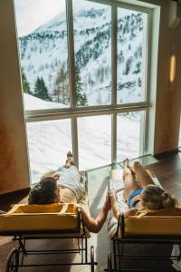 a group of people laying in beds in a room with a window at Appartement & Suiten Hotel Glöcknerin in Obertauern