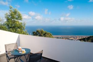 een tafel en stoelen op een balkon met uitzicht op de oceaan bij GuestReady - One happy stay in Machico in Santa Cruz