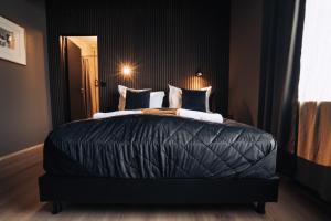 a bedroom with a large bed with black sheets and pillows at Brim Hotel in Reykjavík