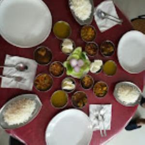 una mesa roja cubierta con platos blancos y magdalenas en Hotel Royal Inn Tripura, en Rādhākishorepur