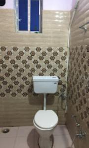 a bathroom with a toilet and a tile wall at Hotel Royal Inn Tripura in Rādhākishorepur
