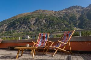 two chairs and a table on a roof with a mountain at Pontresina Youth Hostel in Pontresina