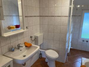 biała łazienka z toaletą i umywalką w obiekcie Ferienhaus Rennsteigblick w mieście Eisfeld