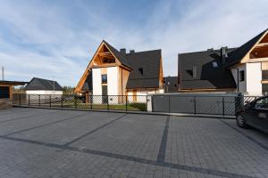 a house with a fence in front of some houses at Apartament VERON w Kościelisku - balkon z widokiem na góry, parking w cenie in Kościelisko