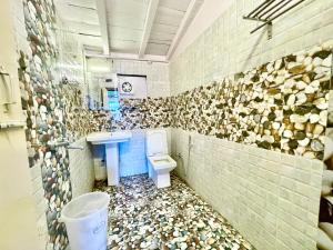 baño con aseo y rocas en la pared en CENTRAL HOTEL by RB group Mall Road-prime-location in-front-of-naini-lake hygiene-and-spacious-room en Nainital