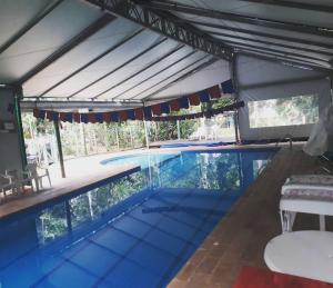 een groot zwembad met een dak erboven met een tafel en stoelen bij Mandala casa 3 dorms cond fech piscina churrasqueira in Boicucanga