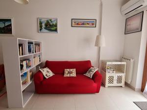ein rotes Sofa im Wohnzimmer mit Bücherregalen in der Unterkunft Cozy studio flat in Rome in Rom
