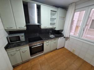 a kitchen with white cabinets and a sink and a microwave at Nuevo! Amplio apto bien ubicado in Santander