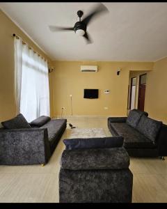 a living room with two couches and a ceiling fan at Zanzibar Homestay in Kiembi Samaki
