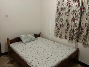 małe łóżko w pokoju z zasłoną w obiekcie Kilimanjaro Ultimate Home Stay w mieście Moshi