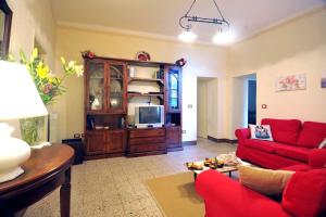 ein Wohnzimmer mit einem roten Sofa und einem TV in der Unterkunft Villa Giara - Piscina vista Lago Trasimeno Umbria in Paciano