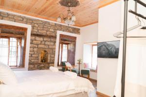een slaapkamer met een wit bed en een stenen muur bij Belaj's House in Gjirokastër