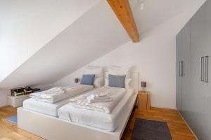 een wit bed met witte lakens en blauwe kussens bij Blaustein Loft in Blaustein