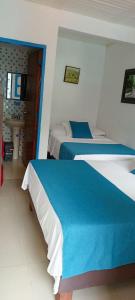 a bedroom with two beds with blue and white sheets at Hostal Bosque de Niebla in Salento