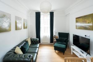 a living room with a black leather couch and two chairs at Elegant 1BR Apartment Near Central London in London