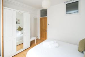 Elegant 1BR Apartment Near Central London في لندن: غرفة نوم بسرير ابيض ومرآة