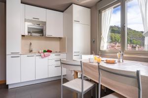 una cocina con armarios blancos y una mesa con sillas. en Apts Spa Cueto 3d 4 adultos, en Cangas de Onís