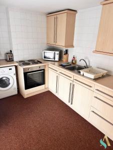 een keuken met een fornuis, een wastafel en een magnetron bij Milton Road Flat 3 TSAC in Hartlepool
