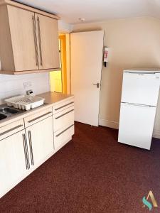 a kitchen with white cabinets and a white refrigerator at Milton Road Flat 3 TSAC in Hartlepool
