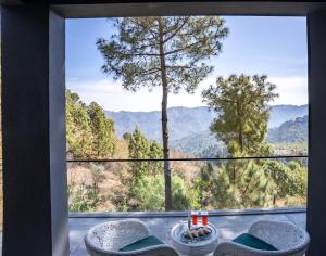 a room with a large window with a view of mountains at Velmore Kasauli Operated by Royal Orchid Hotel Ltd. in Kasauli