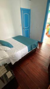 a bed in a room with a blue door at Hostal Bosque de Niebla in Salento