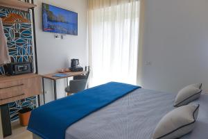 a bedroom with a bed with blue sheets and a television at Charming Rooms Amalfi Coast in Maiori