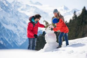 een groep mensen die een sneeuwpop maken in de sneeuw bij Zur Tilli in Neustift im Stubaital
