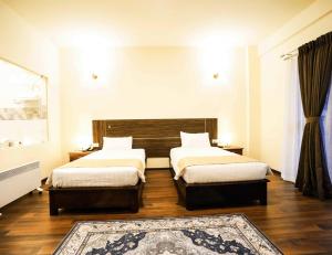 a bedroom with two beds and a rug at Eutsholing Boutique Hotel in Thimphu