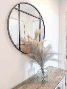 直布羅陀的住宿－E1 Suites & Spa aparthotel style - Gym & Spa，墙上的圆镜子,带羽毛的花瓶