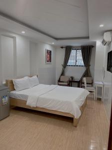 een slaapkamer met een groot wit bed en een bureau bij An's Home Hotel Vũng Tàu in Vung Tau