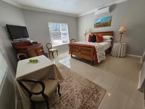 una camera con letto, tavolo e TV di Chocolate Box Guesthouse a Gordonʼs Bay