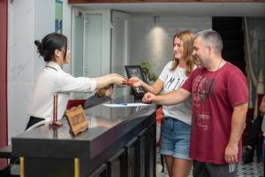 a woman handing a man a plate at a counter at Golden Time Hostel 3 in Hanoi
