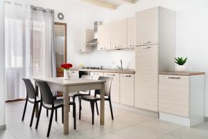 a kitchen with white cabinets and a table and chairs at Ciuriddu Appartamenti in Castellammare del Golfo