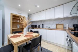 a kitchen with white cabinets and a wooden table at 3 bedroom house in Notting Hill in London