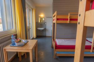 Zimmer mit einem Tisch und einem Etagenbett in der Unterkunft Locarno Youth Hostel in Locarno