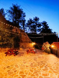 a patio with two picnic tables and lights at Maryloo Country House in Kakopetria