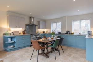 a kitchen with blue cabinets and a table and chairs at Buntings in Walberswick