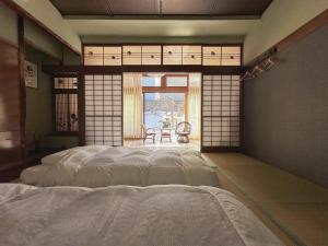een slaapkamer met een bed in een kamer met een raam bij Otarunishikien in Otaru