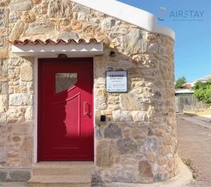 una porta rossa sul lato di un edificio in pietra di Orianna Apartment Airport by Airstay a Spata