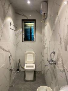 ein weißes Bad mit einem WC und einem Fenster in der Unterkunft Imagine star in Lonavla