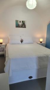 a bedroom with a white bed with a flower on it at Kamaraki Grande Aroniadika in Kythira
