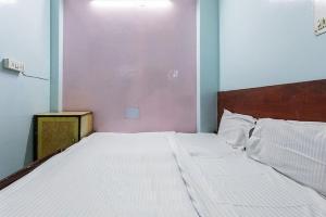 1 dormitorio con 1 cama grande con sábanas blancas en Vanilla hotel, en Bhopal