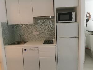 a white kitchen with a microwave and a refrigerator at JIMMYS HOUSE 55 in Beausoleil