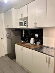eine Küche mit weißen Schränken und einer Mikrowelle in der Unterkunft Departamento 2 habitaciones a 5 min del centro in Trujillo