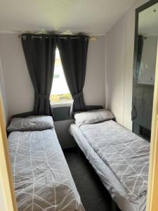 two beds in a small room with a window at Northumberland Caravan Holiday in Cresswell